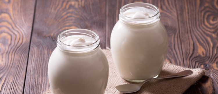 natural yogurt in glass on wooden plank